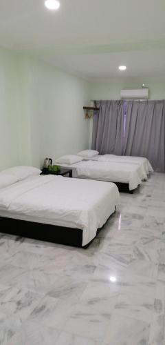 three beds in a room with marble floors at JS Guest House Air Putih - Roomstay in Kuantan