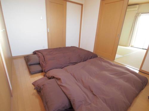 Cama en habitación con sábanas moradas en el suelo en 岡崎Haus, en Okazaki