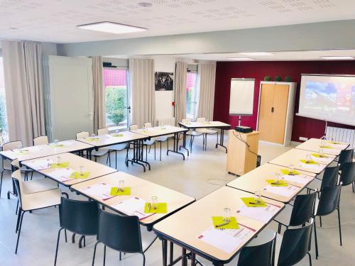 a classroom with tables and chairs and a projection screen at Brit Hotel Mayenne in Mayenne