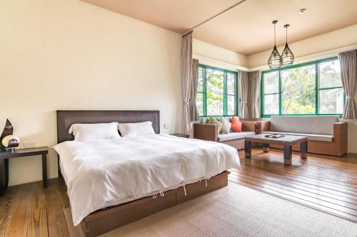 a bedroom with a large bed and a living room at Ville Greensward in Taitung City