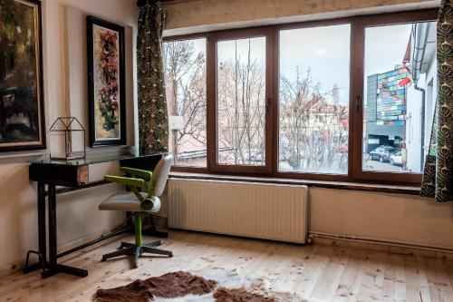 an office with a desk and a chair and windows at Apartament Art Cluj in Cluj-Napoca