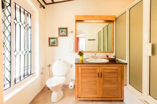 een badkamer met een toilet, een wastafel en een spiegel bij Teanest by Nature Resorts in Coonoor