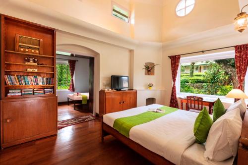 een slaapkamer met een groot bed en een televisie bij Teanest by Nature Resorts in Coonoor