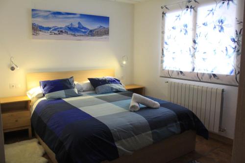 1 dormitorio con 1 cama con manta azul y blanca en Casa MENDILUCE, en El Pueyo de Jaca