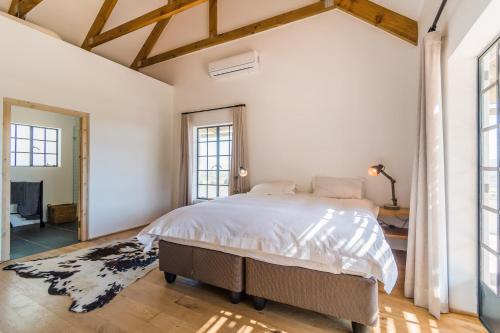 1 dormitorio con 1 cama grande y ventanas grandes en Druk My Niet Wine Estate en Paarl
