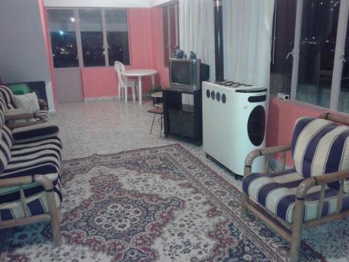a living room with two chairs and a tv at Bauhaus Motel in Bcharré