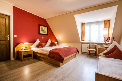 a hotel room with a bed and a red wall at Hotel Neuwarft in Dagebüll