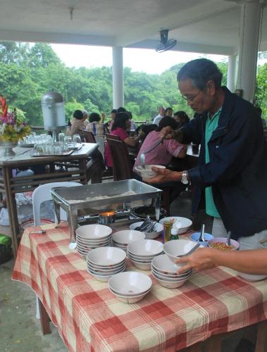 a man standing at a table with plates of food at Baantantara in Suan Phung