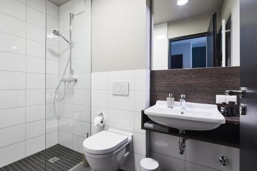 a white bathroom with a toilet and a sink at ipartment Wolfsburg in Wolfsburg