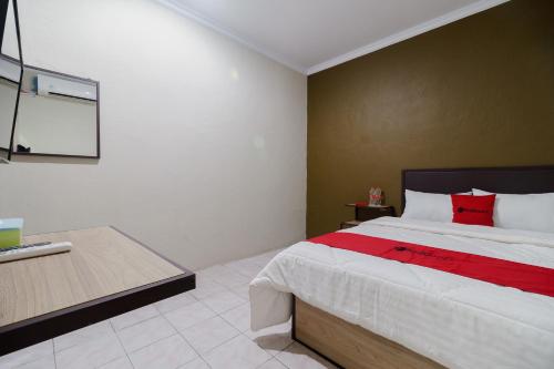 um quarto com uma cama grande e uma almofada vermelha em RedDoorz near Cikampek Mall Karawang em Karawang