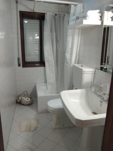 a white bathroom with a toilet and a sink at Casa Sr do Calvário in Paços de Ferreira
