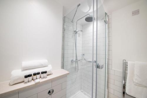 a white bathroom with a shower with white tiles at The Five Bells by Innkeeper's Collection in Weston Turville