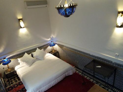 a bedroom with a white bed and a chandelier at Dar Abdesalam in Fès