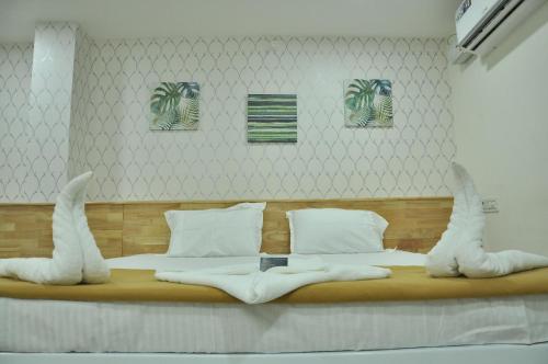 a bedroom with a large bed with white sheets at ADITI ROOMS in Tiruchchirāppalli