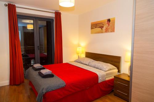 um quarto com uma cama com um cobertor vermelho em City 3 Bedroom Ensuited apartment with parking em Dublin