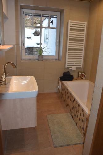 baño con bañera, lavabo y ventana en Ferienhaus Saxenauer en Hinterstoder