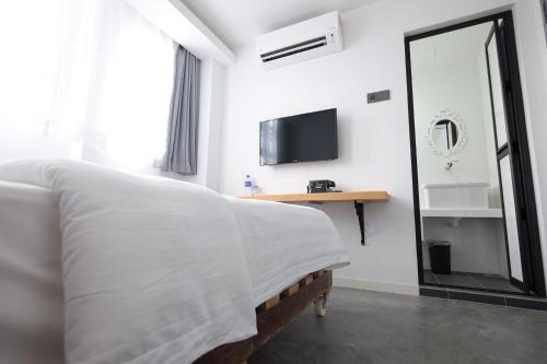 a white bedroom with a bed and a mirror at White Loft Hotel in Melaka