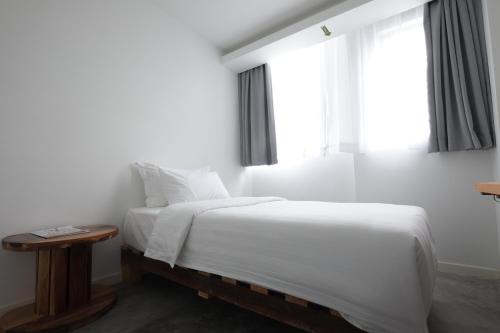 a white bedroom with a bed and a window at White Loft Hotel in Melaka