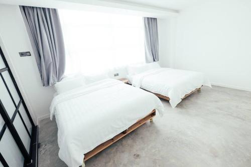 two twin beds in a room with a window at White Loft Hotel in Melaka