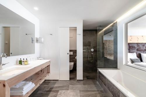 a bathroom with a tub and a sink and a shower at Sporthotel Sonne in Alpe di Siusi