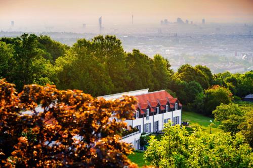 ウィーンにあるPalace Hostel Viennaの木立の丘の上に赤い屋根の家