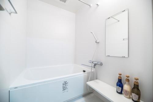 baño con paredes blancas, espejo y botellas en KYOSTAY Iroha Toji Main, en Kioto