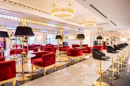 a lobby with red chairs and tables and chandeliers at Hotel Ariston in Paestum