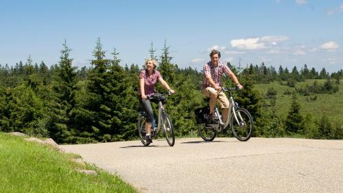 a man and woman riding bikes down a road at Wellness-& Nationapark Hotel Schliffkopf, BWSC in Baiersbronn