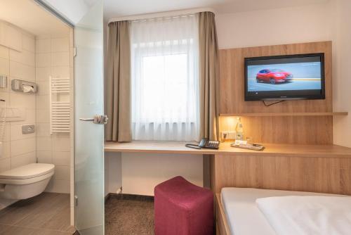 a hotel room with a bed and a tv and a bathroom at Hotel Gasthof Zum Rössle in Heilbronn