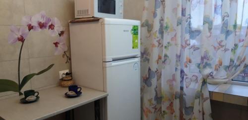 einen weißen Kühlschrank in einer Küche mit einem Vorhang in der Unterkunft Apartment on Kamyanetskaya street in Chmelnyzkyj