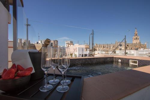 twee wijnglazen en een kom aardbeien op een tafel bij Cathedral Private Pool Penthouse in Sevilla