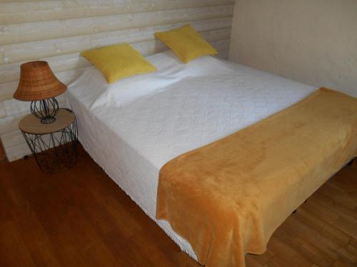 a white bed with yellow pillows and a lamp at Jolie chambre entre mer et campagne in Assérac