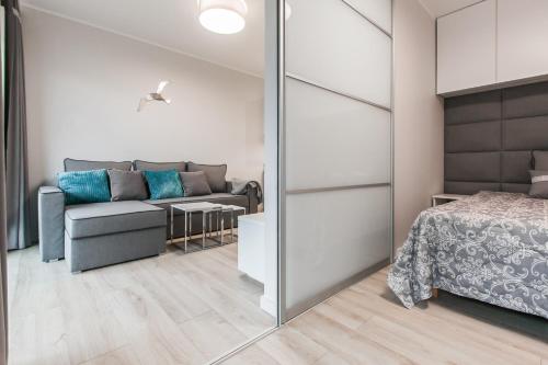 a bedroom with a couch and a bed and a mirror at Apartamenty Studio Gardenia in Dziwnów