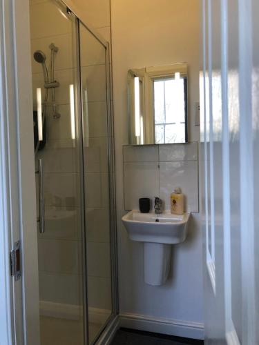 ein Bad mit einem Waschbecken und einer Dusche mit einem Spiegel in der Unterkunft Fishergate ApartHotel 2 - City Centre Location in Preston