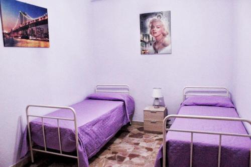 two beds in a room with purple sheets at Umberto I - Affitti brevi in Favara