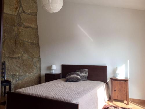 a bedroom with a bed and a stone wall at Quinta do Pêso in Amarante
