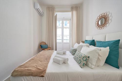 a white bedroom with a large bed with blue and white pillows at Casa Portuguesa Chiado 25 in Lisbon