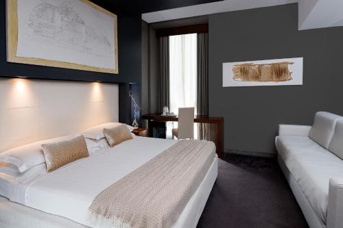 1 dormitorio con cama blanca y sofá en Metropolis - Hotel di Charme, en Roma
