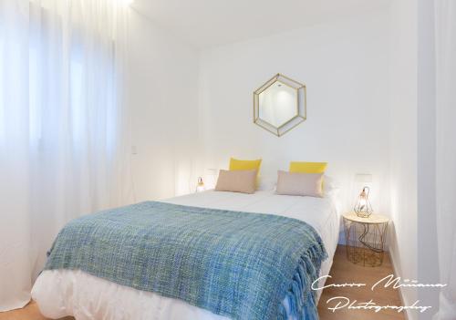 a bedroom with a bed with a blue blanket and a mirror at Apartamento con gran azotea in Marbella