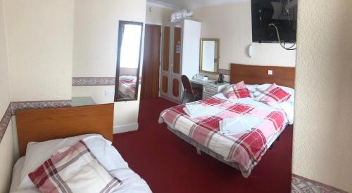 a hotel room with two beds and a mirror at Silversands Hotel in Blackpool