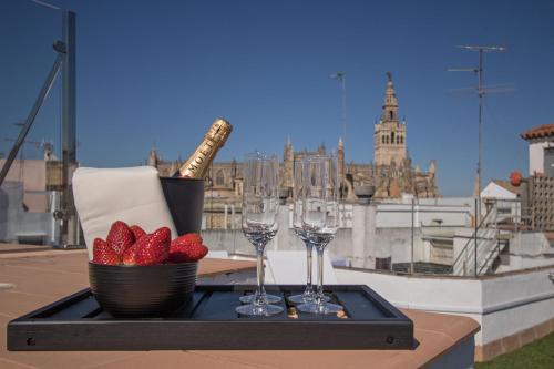 een dienblad met wijnglazen en aardbeien op een balkon bij Cathedral Private Pool Penthouse in Sevilla