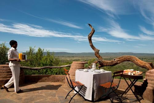 a woman standing on a terrace with a table with at Madikwe Safari Lodge in Madikwe Game Reserve