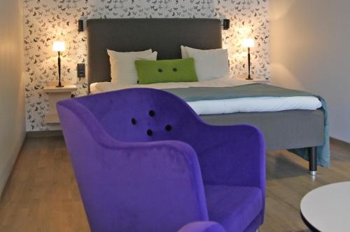 a bedroom with a purple chair and a bed at Hestraviken Hotell & Spa in Hestra