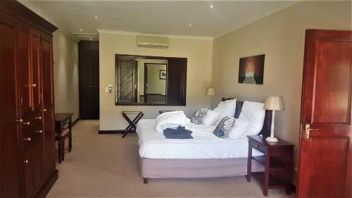 a bedroom with a large white bed and a mirror at Traders Guesthouse at Lake Pleasant Living in Sedgefield