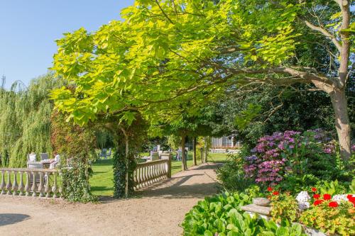 ein Park mit einer Bank, Blumen und Bäumen in der Unterkunft Hotel Pension 't Huys Grol in Renesse