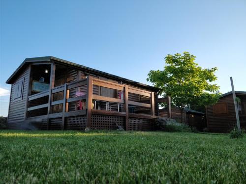 a large wooden house with a green field in front of it at La Facera, Cabañas de Madera in Valparaíso