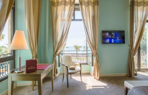 Cette chambre comprend un lit, un bureau et une fenêtre. dans l'établissement Westminster Hotel & Spa Nice, à Nice