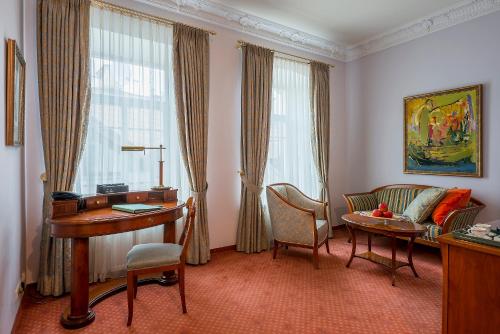 a living room with a desk and a couch and a table at Grotthuss Boutique Hotel Vilnius in Vilnius