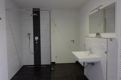a bathroom with a shower and a sink and a mirror at Sweet Park Appartements in Rheinhausen
