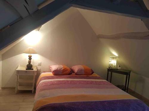 ein Schlafzimmer mit einem Bett und einer Lampe im Dachgeschoss in der Unterkunft CALME ET AUTHENTICITE AU COEUR DU COURTGAIN in Saint-Valery-sur-Somme